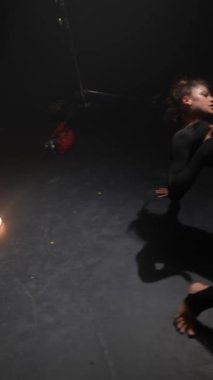 Loş bir stüdyoda, genç bir bayan çağdaş bir dans gösterisi yapıyor. Yüksek kalite 4k görüntü