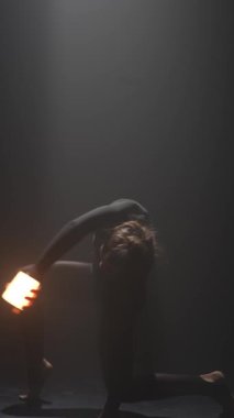 Karanlık bir stüdyoda genç ve şık bir koreograf tarafından yapılan dikkate değer modern dans hareketleri. Yüksek kalite 4k görüntü