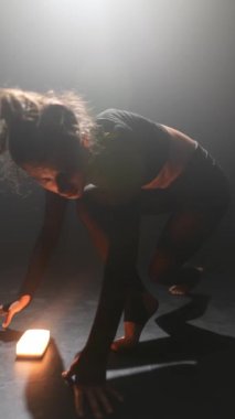 Siyahlar içinde güzel bir bayan loş bir stüdyoda modern bir dans sergiliyor. Yüksek kalite 4k görüntü