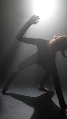 Genç kadın, bir dansçı, yumuşak ışıklandırılmış bir stüdyoda modern bir dans gerçekleştiriyor. Yüksek kalite 4k görüntü