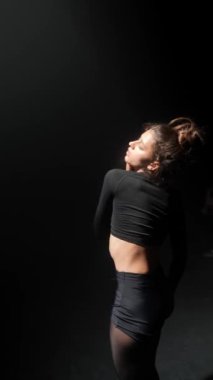 Genç bir kadın karanlık bir stüdyoda çağdaş dans ediyor. Yüksek kalite 4k görüntü