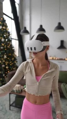 Sportif genç bir kadın Noel sezonu boyunca pratik yapmak için sanal gerçeklik kulaklığı kullanıyor. Yüksek kalite 4k görüntü