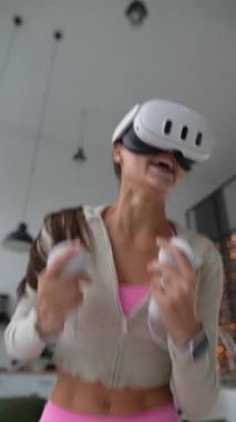 Spor giyimli, muhteşem bir kadın sanal gerçeklik kulaklığı hediye edilmiş bir video oyunundan enerji dolu bir şekilde zevk alıyor. Yüksek kalite 4k görüntü