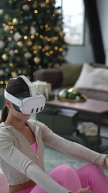 Sanal gerçeklik kulaklığı ile, güzel bir genç kadın ev egzersizi sırasında bacak egzersizi yapıyor. Yüksek kalite 4k görüntü