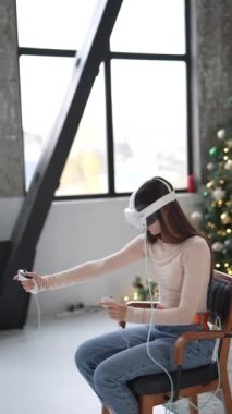 Genç bir kadın Noel süslü bir evde sanal gerçeklik kulaklığıyla oyun oynarken hoş bir anı yakalamak. Yüksek kalite 4k görüntü