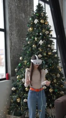 Noel ağacı, sanal gerçeklik kulaklığı kullanan genç ve şık bir kadın için zemin görevi görüyor. Yüksek kalite 4k görüntü