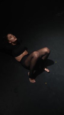 Çağdaş dansla meşgul olan genç kadın, karanlık stüdyoda zarafetle hareket ediyor. Yüksek kalite 4k görüntü