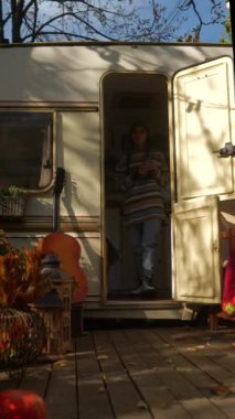 Karavanın dışındaki terasta bir sonbahar gününün sıcaklığını emen çekici bir hippi kız. Yüksek kalite 4k görüntü