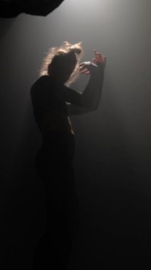 Gizemli genç bir bayan yarı karanlıkta çağdaş bir parça dans ediyor. Yüksek kalite 4k görüntü