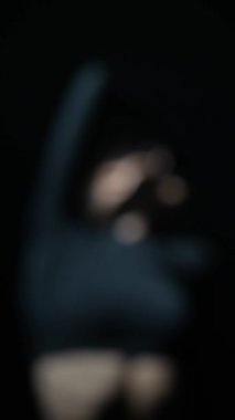 Loş bir stüdyoda dans eden, siyah elbiseli çarpıcı bir kadın modern bir gösteri sergiliyor. Yüksek kalite 4k görüntü