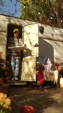 Karavanın önündeki terasta bir sonbahar gününün sıcağında güneşlenen çekici bir hippi kız. Yüksek kalite 4k görüntü