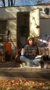 Sonbahar günü güneşli bir karavanın yanında hippi kıyafeti giymiş şık genç bir bayan. Yüksek kalite 4k görüntü
