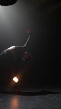 Muhteşem bir kadın ışık tutarken modern dansın koreografik hareketlerini sergiliyor. Yüksek kalite 4k görüntü