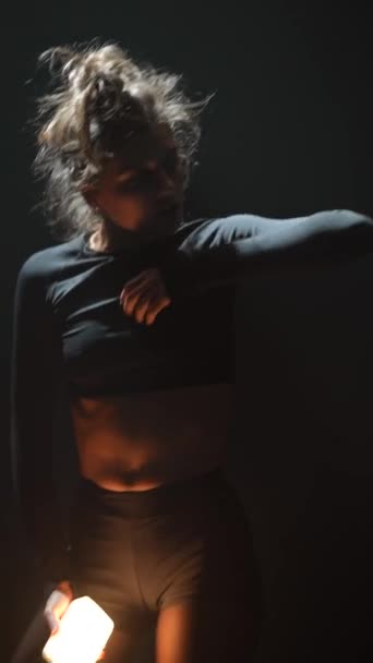 黒い服を着た美しい女の子は 薄暗く照らされたスタジオでモダンな振付を踊っています 高品質の4K映像 — ストック動画