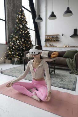 Yoga yapıyor, pembe spor kıyafetleri giyiyor ve sanal gerçeklik gözlükleri takıyor. Yüksek kalite fotoğraf