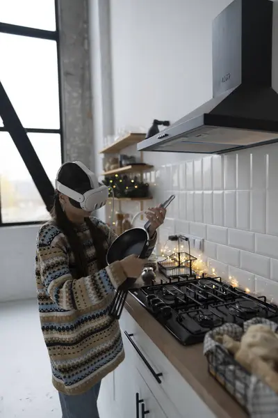 在喜庆的厨房里 一个漂亮而时尚的女孩正在一个虚拟现实耳机的帮助下按照食谱做饭 高质量的照片 — 图库照片