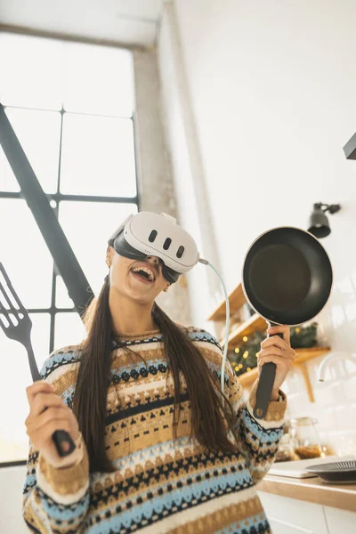 一个年轻美丽的女人穿着一副虚拟现实的耳机在厨房里做饭 高质量的照片 — 图库照片