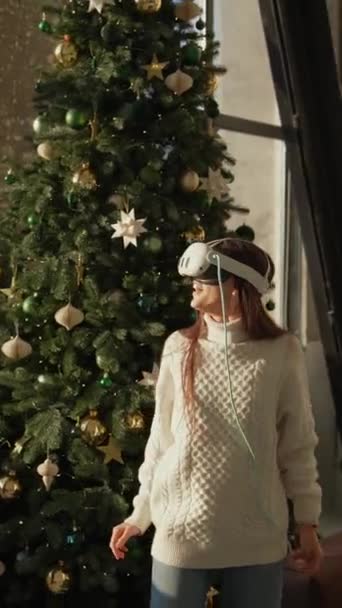 一位可爱的年轻女士正在通过虚拟的现实眼镜探索圣诞树 高质量的4K镜头 — 图库视频影像