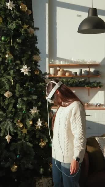 一位漂亮的年轻女子戴着一副虚拟现实的眼镜 正在检查一棵圣诞树 高质量的4K镜头 — 图库视频影像