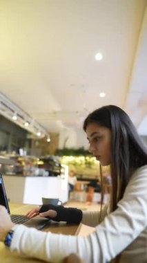 Bir kafede, bir tıp fakültesi öğrencisi internetten öğreniyor, hem bir telefon hem de bir dizüstü bilgisayar kullanıyor. Yüksek kalite 4k görüntü