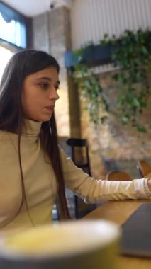 Bir kafede, bir tıp fakültesi öğrencisi çevrimiçi okuyor ve hem bir telefon hem de bir dizüstü bilgisayar kullanıyor. Yüksek kalite 4k görüntü