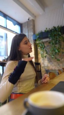 Genç, güzel bir öğrenci bir kafede dizüstü bilgisayarla oturuyor ve sohbet ediyor. Yüksek kalite 4k görüntü