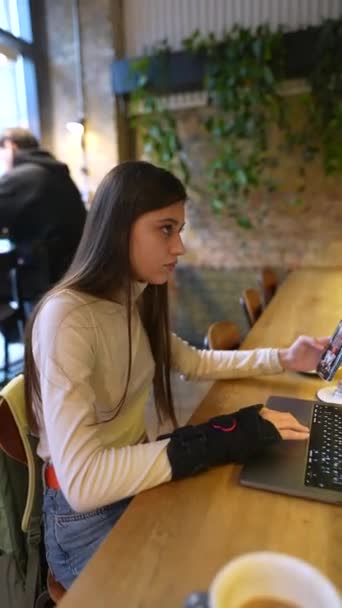 坐在咖啡馆里的是一个年轻而有魅力的学生 他带着笔记本电脑 在聊天 高质量的4K镜头 — 图库视频影像
