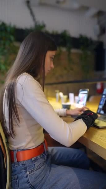 대학의 학생은 카페에서 전화기와 노트북을 사용하여 온라인 학습에 종사하고 있습니다 — 비디오