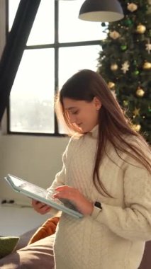 Genç ve güzel bir bayan, Noel tatili boyunca bir tabletle internetten iletişim kuruyor. Yüksek kalite 4k görüntü