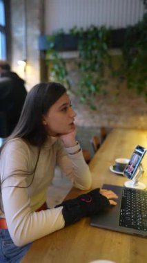 Bir kafede, genç ve sevimli bir öğrenci dizüstü bilgisayarıyla oturur ve sohbet eder. Yüksek kalite 4k görüntü