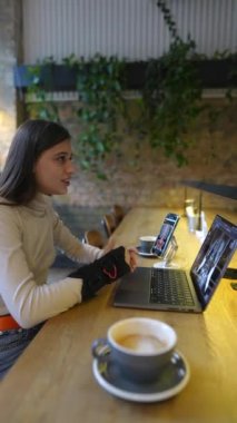 Bir kafe ortamında, genç bir tıp fakültesi öğrencisi bir dizüstü bilgisayarla online eğitime katılıyor. Yüksek kalite 4k görüntü