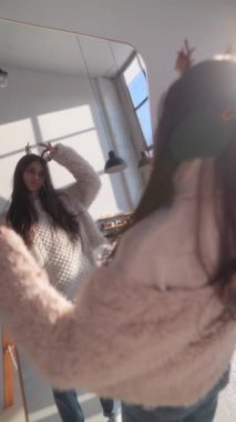 Aynanın önünde, sevimli genç bir kız Noel geyiği maskesi takarken dans ediyor. Yüksek kalite 4k görüntü