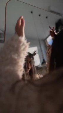 Gençliğinde süslenen güzel bir kız, evinde aynanın önünde Noel geyiği maskesi deniyor. Yüksek kalite 4k görüntü