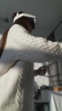 Sanal bir oyuna dalmış, sevimli genç bir kadın evde üç boyutlu sanal gerçeklik gözlüğü takıyor. Yüksek kalite 4k görüntü