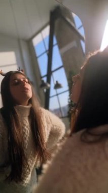 Genç ve güzel bir kız Noel geyiği maskesini ev aynasının önüne takıyor. Yüksek kalite 4k görüntü