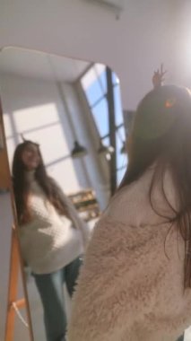 Tatlı genç bir kadın aynanın önünde Noel geyiği maskesi takarak dans ediyor. Yüksek kalite 4k görüntü