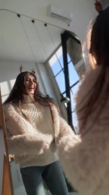 Noel geyiği maskesi takmış genç bir kız aynada kendine hayran. Yüksek kalite 4k görüntü