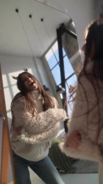 Aynada kendine hayran olan genç bir kadın, Noel geyiği maskesi takıyor. Yüksek kalite 4k görüntü