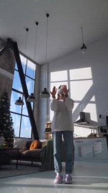 Arka planda Noel ağacı olan bir dairede sanal gerçeklik kulaklığı takan güzel bir genç kadın. Yüksek kalite 4k görüntü