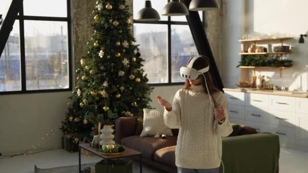 一位漂亮的年轻女士正在圣诞树旁调整一个虚拟现实耳机 高质量的4K镜头 — 图库视频影像