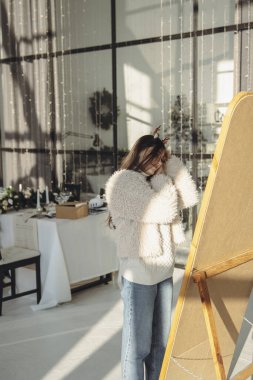 Neşeyi kucaklayan, Noel geyiği maskeli canlı genç bir bayan evde mutlu bir şekilde gülümsüyor. Yüksek kalite fotoğraf