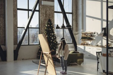 Şenlikli bir Noel atmosferinde, açık giysili ve sanal gerçeklik kulaklıklı genç bir bayan aynada kendine bakıyor. Yüksek kalite fotoğraf