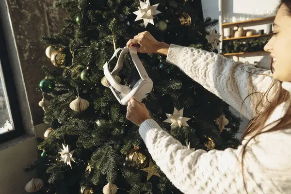 一个被圣诞树框成的女孩 手里拿着一个虚拟现实耳机 高质量的照片 免版税图库照片