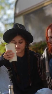 Sonbahar manzarasının ortasında, hippi kıyafetli iki çekici genç bayan bir karavanın keyfini çıkarıyorlar. Yüksek kalite 4k görüntü