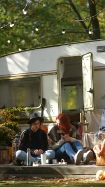 Şık genç kadınlar, hippi havası yaratıyorlar, bir sonbahar inzivasında bir karavanla rahatlıklarının tadını çıkarıyorlar. Yüksek kalite 4k görüntü