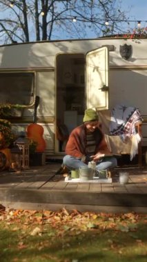 Güz bahçesindeki karavan terasında gitar ve sıcak içecek termosuyla şık, şık, şık bir hippi kız. Yüksek kalite 4k görüntü