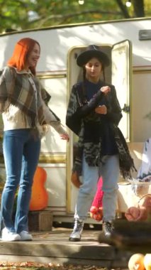 Modayı takip eden genç bayanlar, hippi görünüşü takınmak, sonbahar kampında bir karavanla eğlenmek. Yüksek kalite 4k görüntü