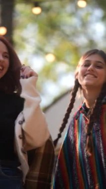 Hippi tarzı giyinmiş iki güzel genç bayan, sonbahar parkındaki bir karavanda eğleniyorlar. Yüksek kalite 4k görüntü