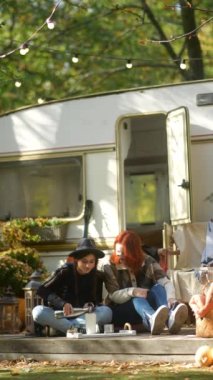 Şık hippi kıyafetleriyle, modern genç bayanlar bir sonbahar kampında karavanıyla vakit geçirmekten zevk alıyorlar. Yüksek kalite 4k görüntü