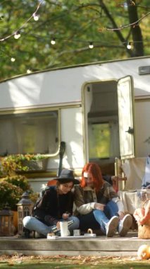 Moda ve tasasız, hippi kıyafetli genç kızlar sonbahar aylarında bir karavanla eğleniyorlar. Yüksek kalite 4k görüntü